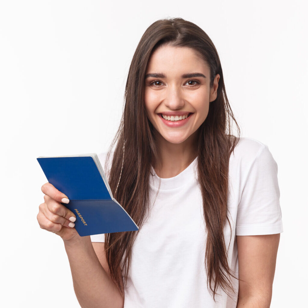 Travelling, holidays, summer concept. Close-up portrait of cute, happy pretty young woman in t-shirt, holding opened passport and smiling, standing in airport terminal going for journey, vacation.